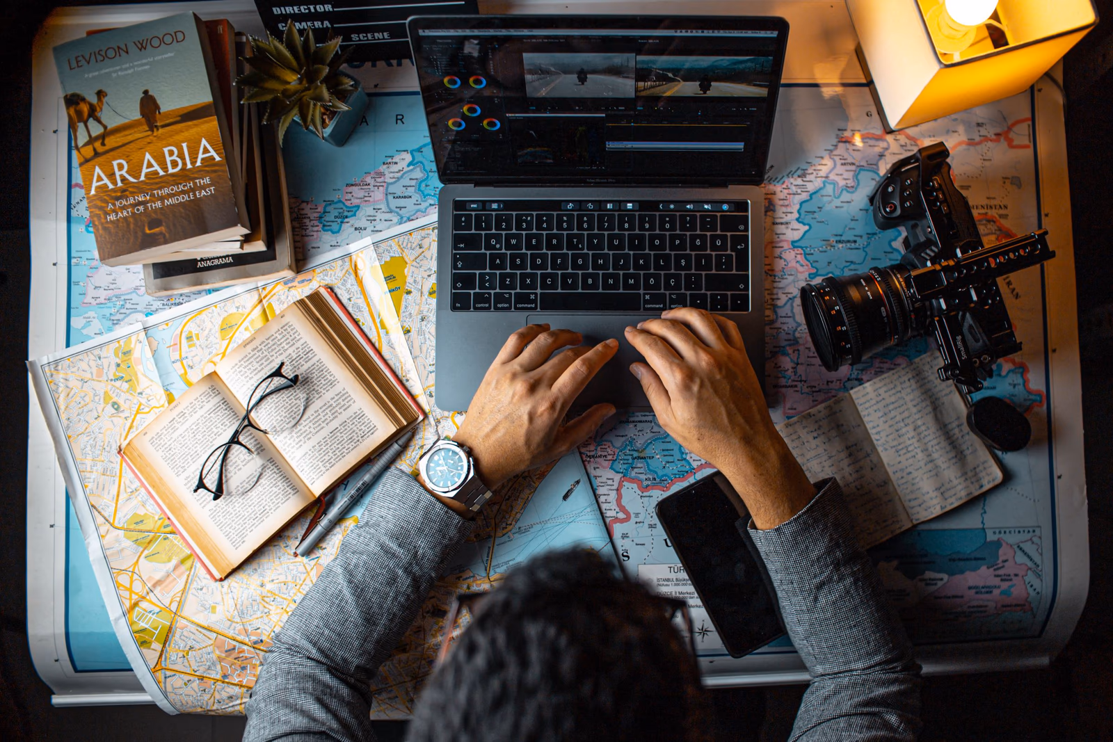 Laptop, Karten und Reisebuch auf einem Schreibtisch