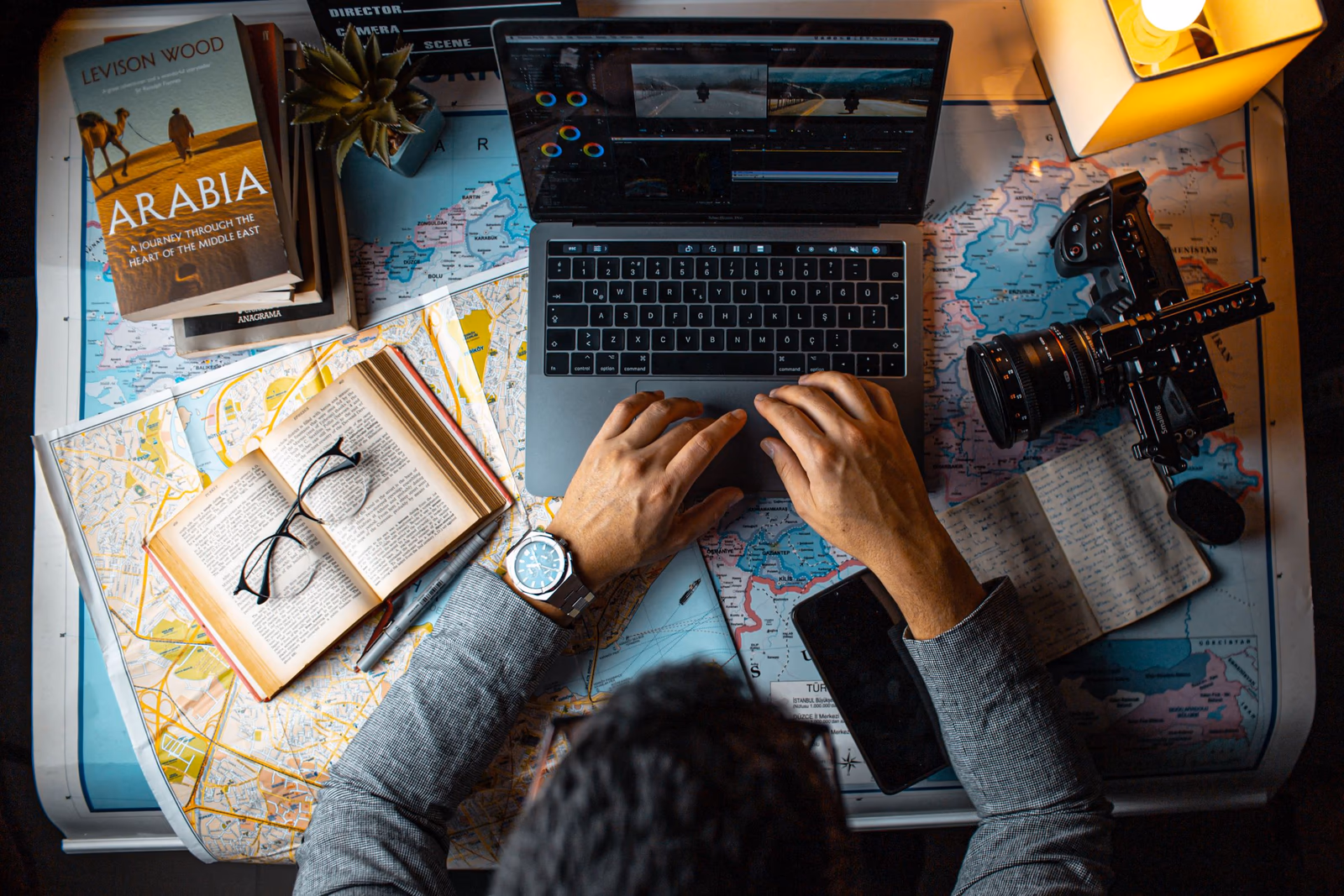 Laptop, Karten und Reisebuch auf einem Schreibtisch