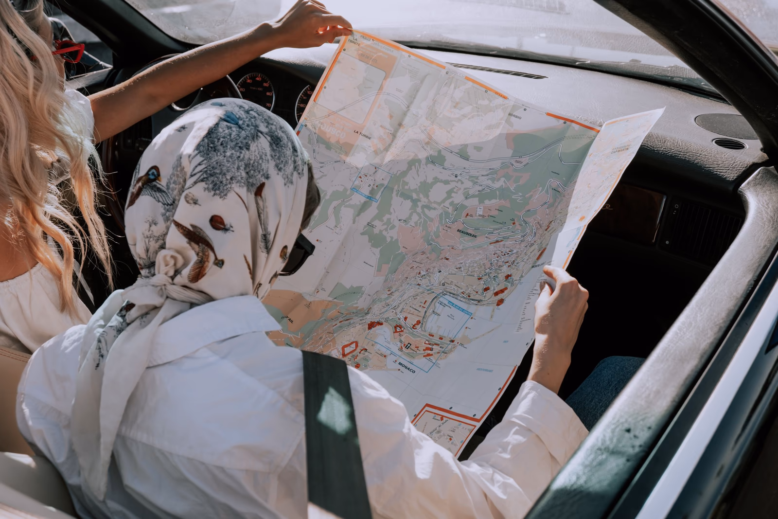 Zwei Freundinnen planen in einem Auto ihre Route mit einer Straßenkarte