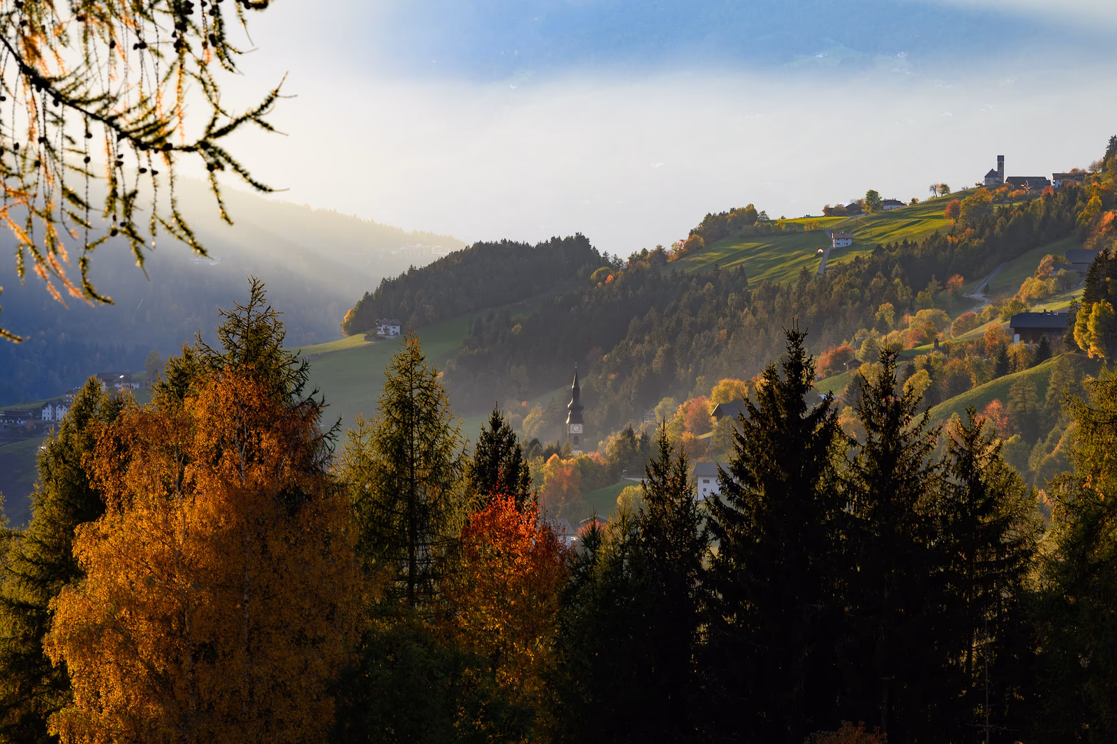 Herbstliche Hänge und Kirchtürme bei St. Magdalena in Villnöss im Abendlicht