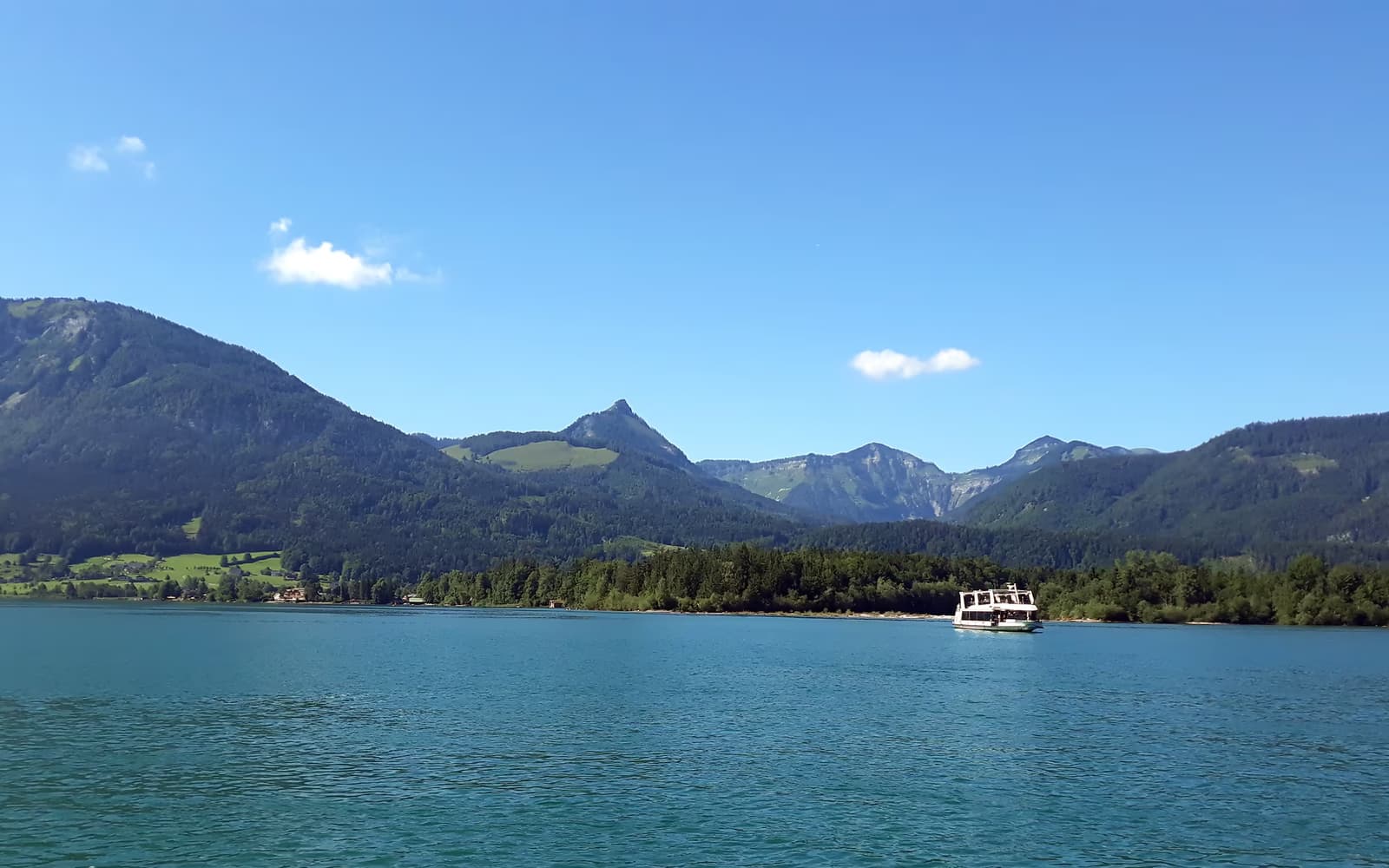 Wolfgangsee mit bewaldeten Bergen und einem Ausflugsschiff