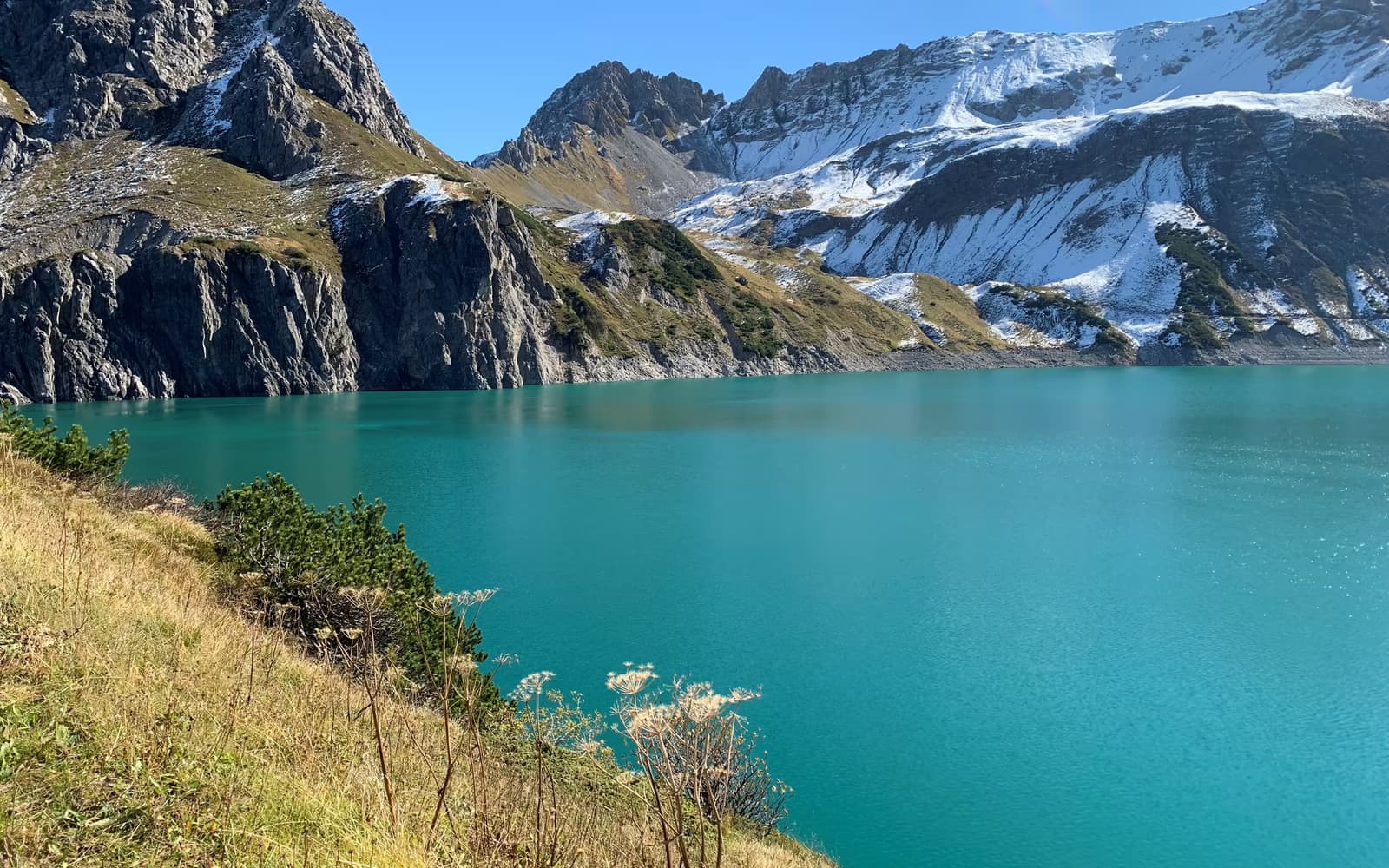 Türkisfarbener Lünersee vor felsigen und verschneiten Berghängen