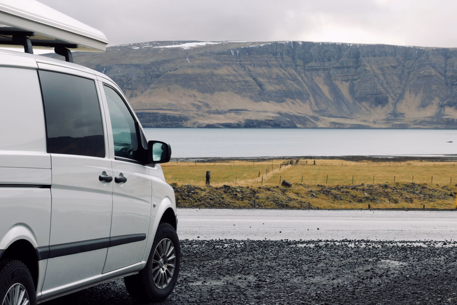 Campervan vor einer isländischen Berg- und Seenlandschaft