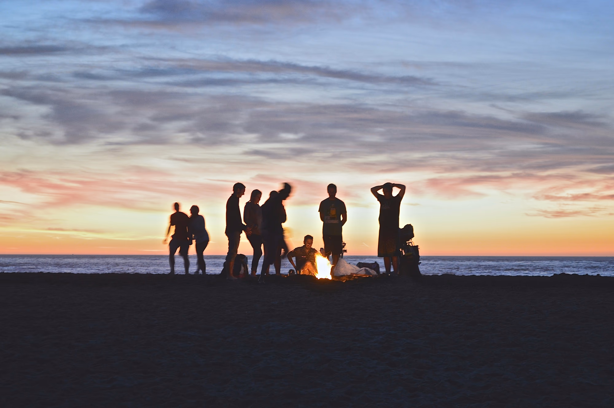Freundesgruppe sitzt bei Sonnenuntergang gemeinsam am Strand