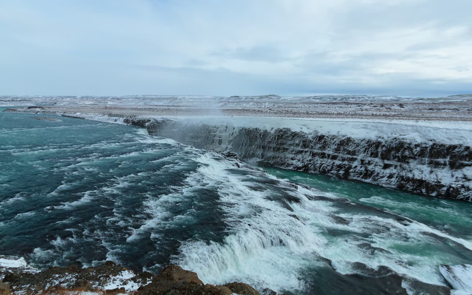 Gullfoss mit vereisten Felskanten und türkisfarbenem Wasser im Winter