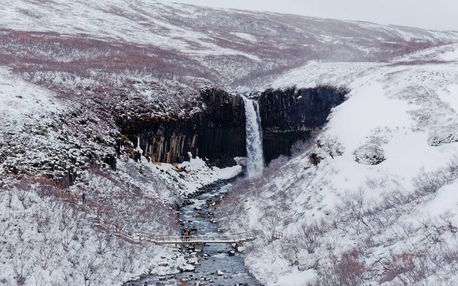 Svartifoss vor dunklen Basaltsäulen in einer verschneiten Landschaft