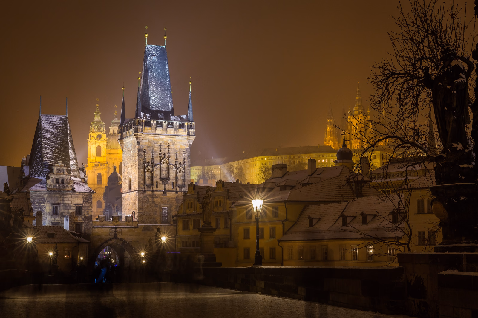 Karlsbrücke in Prag in einer verschneiten Winternacht mit Kleinseitner Brückenturm und angestrahlter Burg