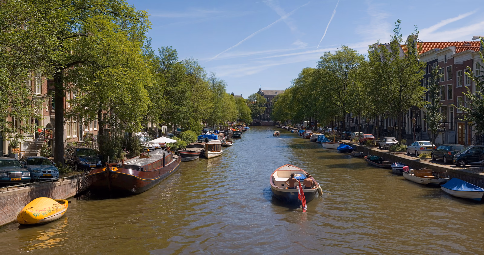 Gracht mit Häusern und Bäumen in Amsterdam; Motivaufnahme im Sommer