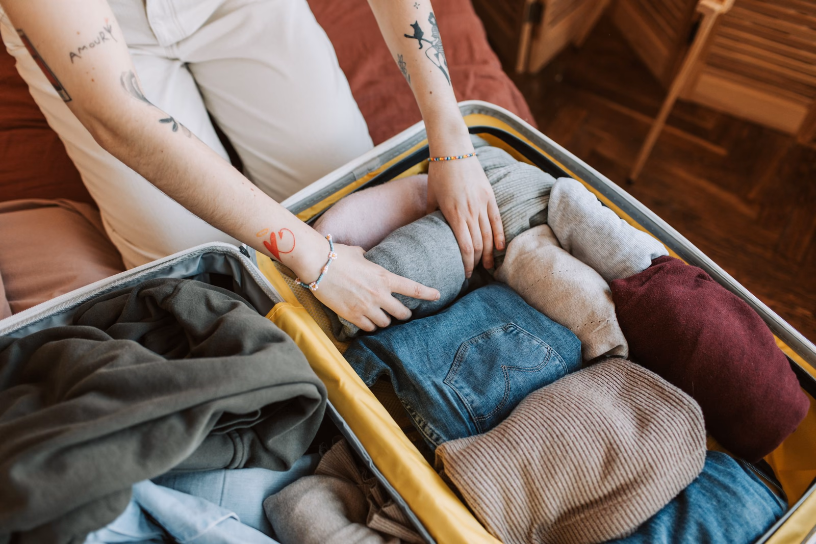 Eine Person packt warme Kleidung in einen Koffer.