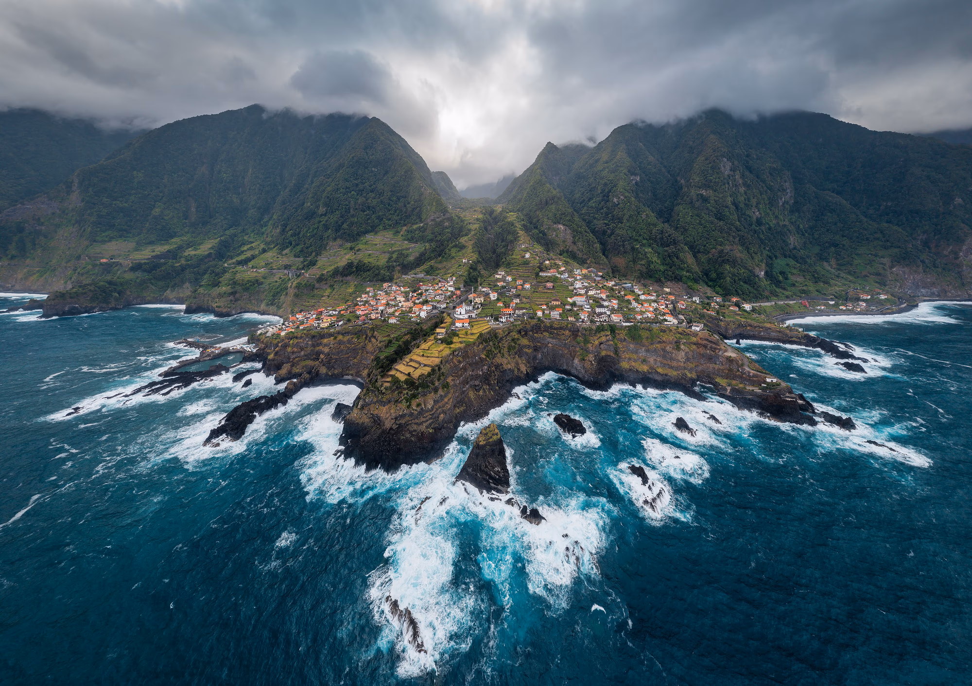 Dramatische Küste bei Seixal auf Madeira mit Atlantik, Häusern und grünen Bergen