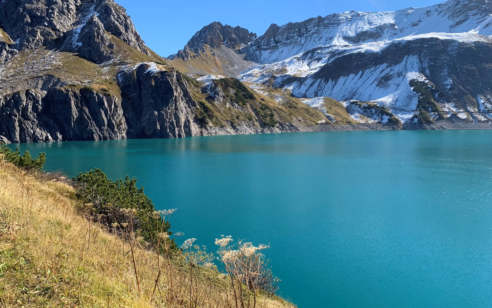 Türkisfarbener Lünersee vor felsigen und verschneiten Berghängen