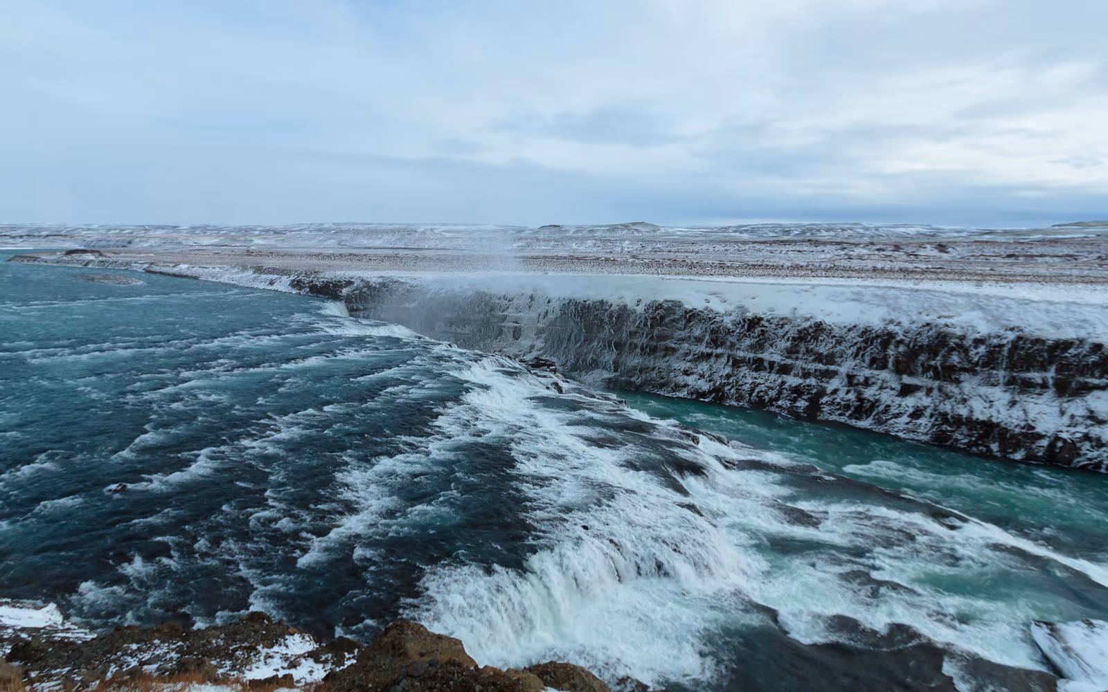 Gullfoss mit vereisten Felskanten und türkisfarbenem Wasser im Winter
